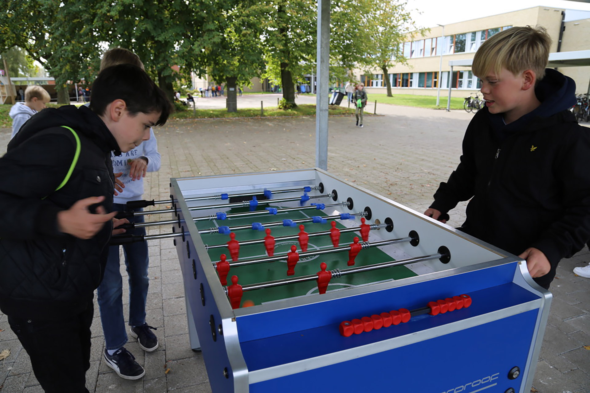 speelplaats met leerlingen aan kickertafel 